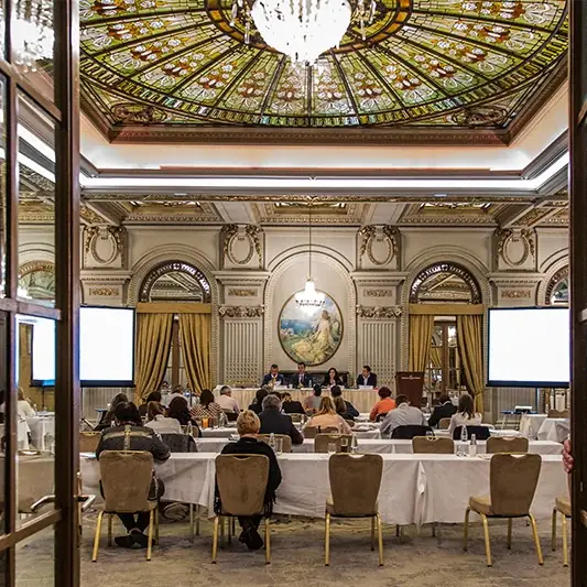 Sala Le Diplomate văzută prin ușile deschise, cu cupola de vitraliu, tabloul rotund și prezidiul
